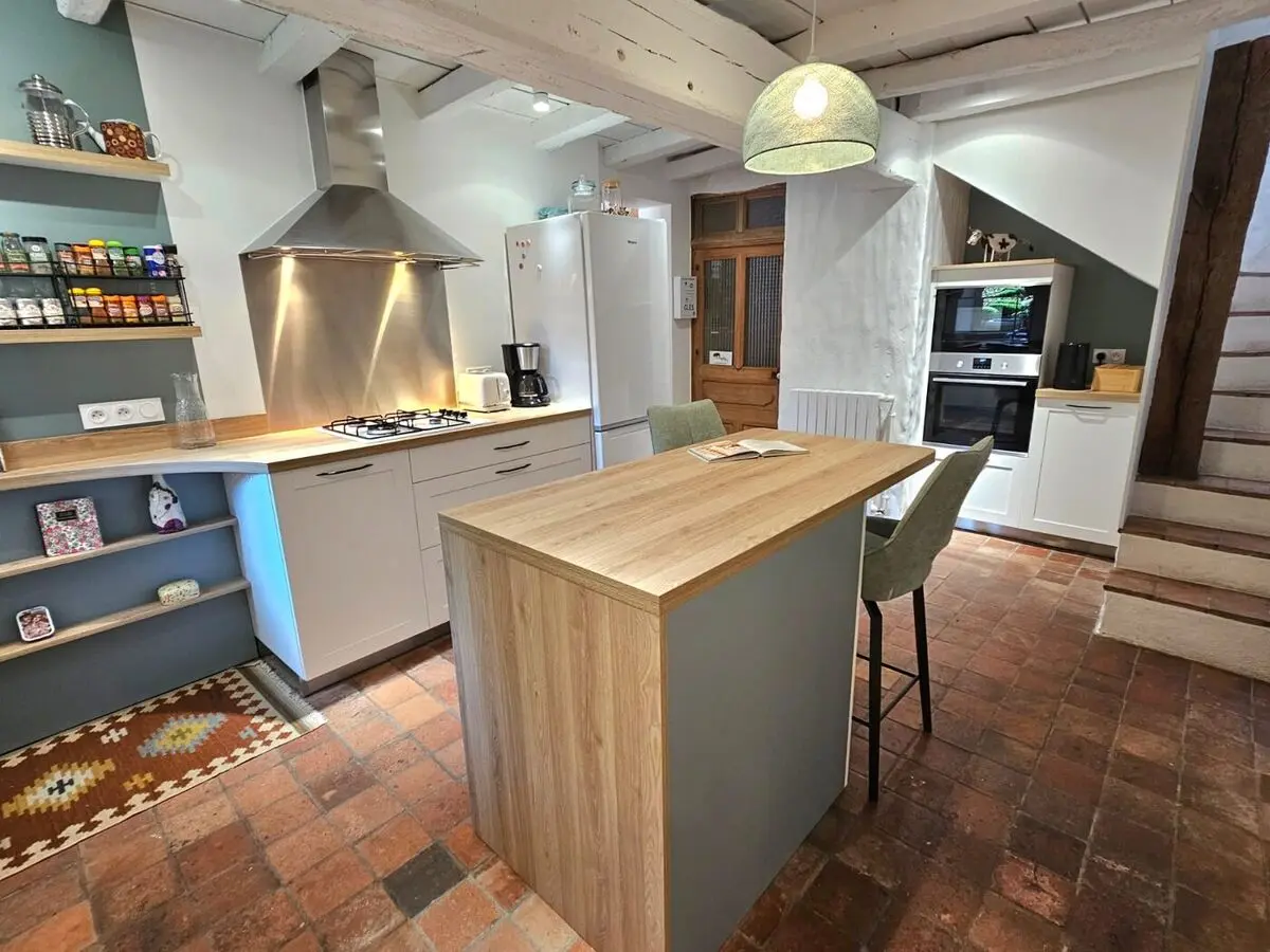 Cuisine blanche et bois avec îlot central et colonne sous escalier